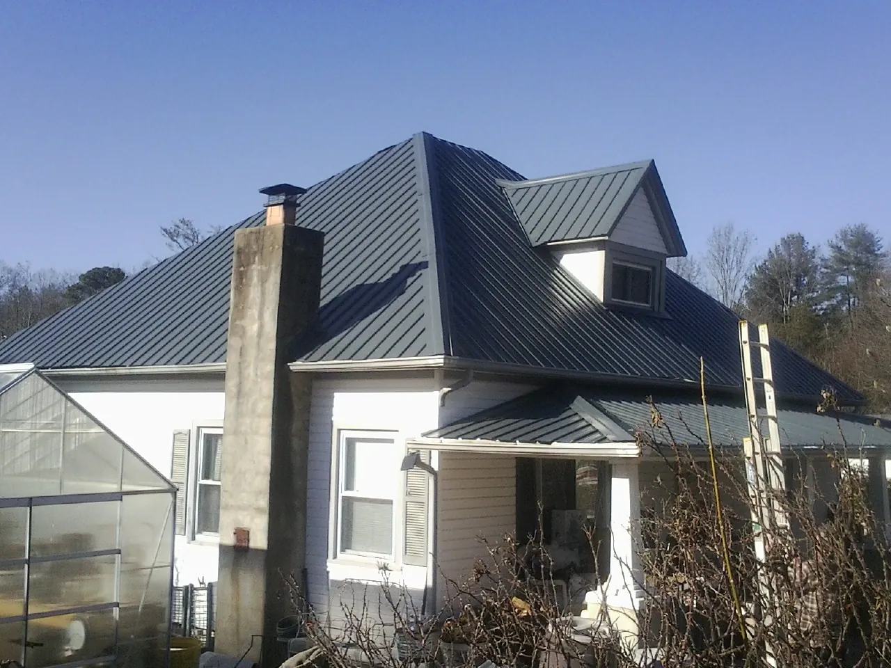 Dark blue standing seam metal roof on a white farmhouse with dormer — Slate & Tile Roof Repair by Roofing Brothers in Altaville