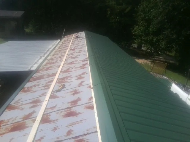 Old rusted panels beside newly installed green metal roofing — Wind Damage Roof Repair by Roofing Brothers in Altaville