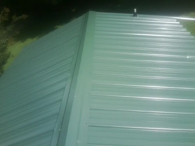 New green metal panels meeting at the ridge of a roof — Flat Roof Repair work by our crew in Altaville