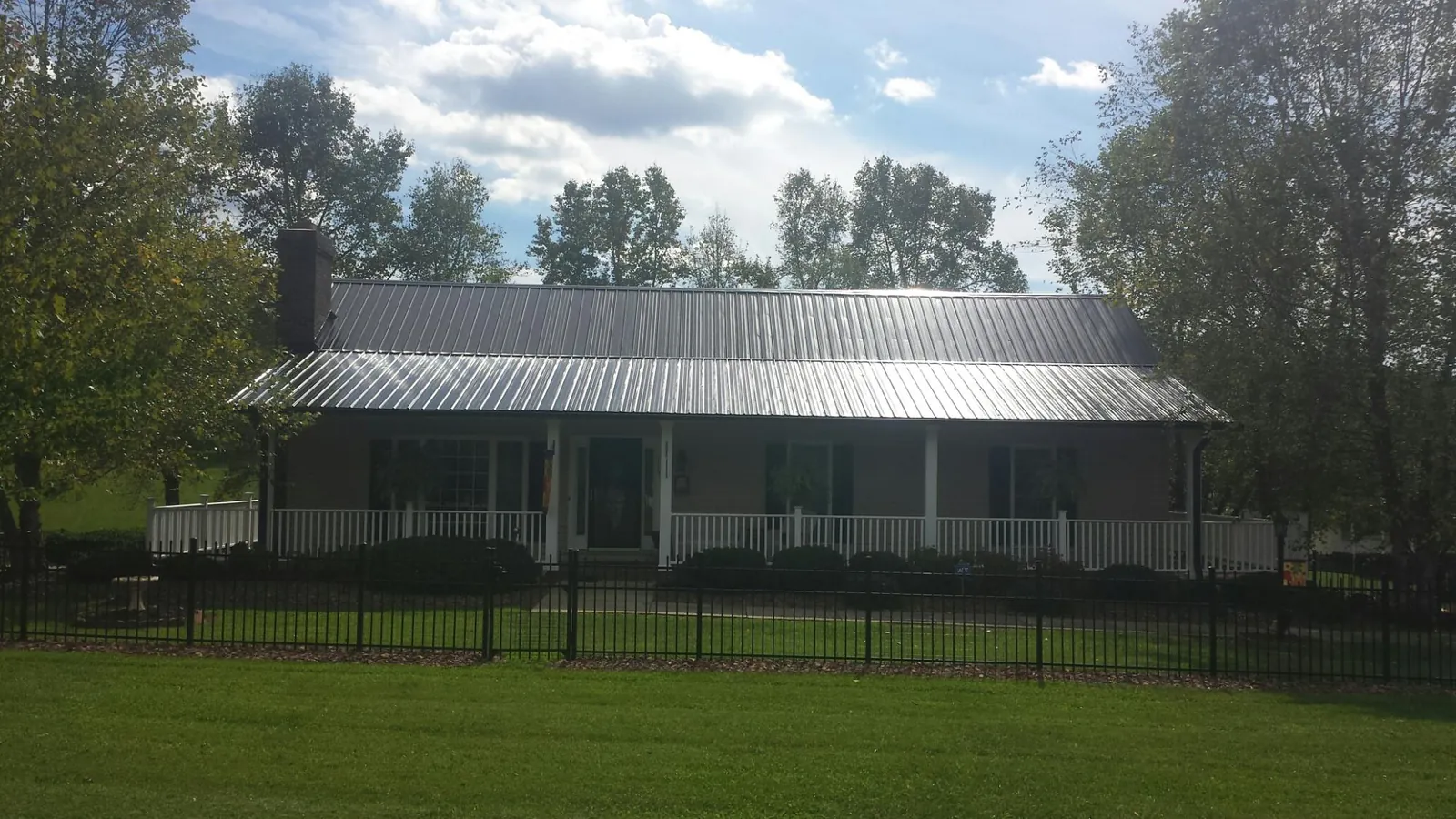 Gray metal roof on a brick ranch with a full width front porch — Gutter Guard Installation work by our crew in Altaville