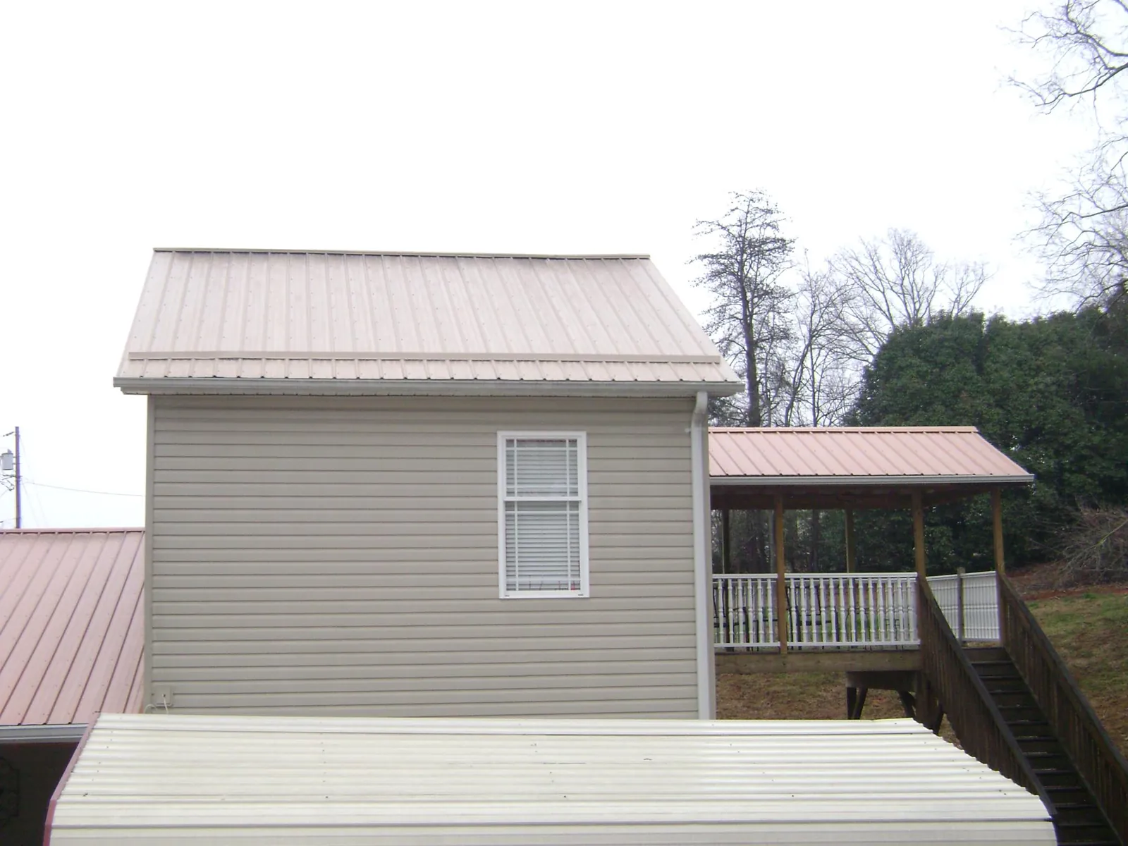 Tan metal roofs on a two story addition and attached porch, from a Roof Replacement job in Altaville