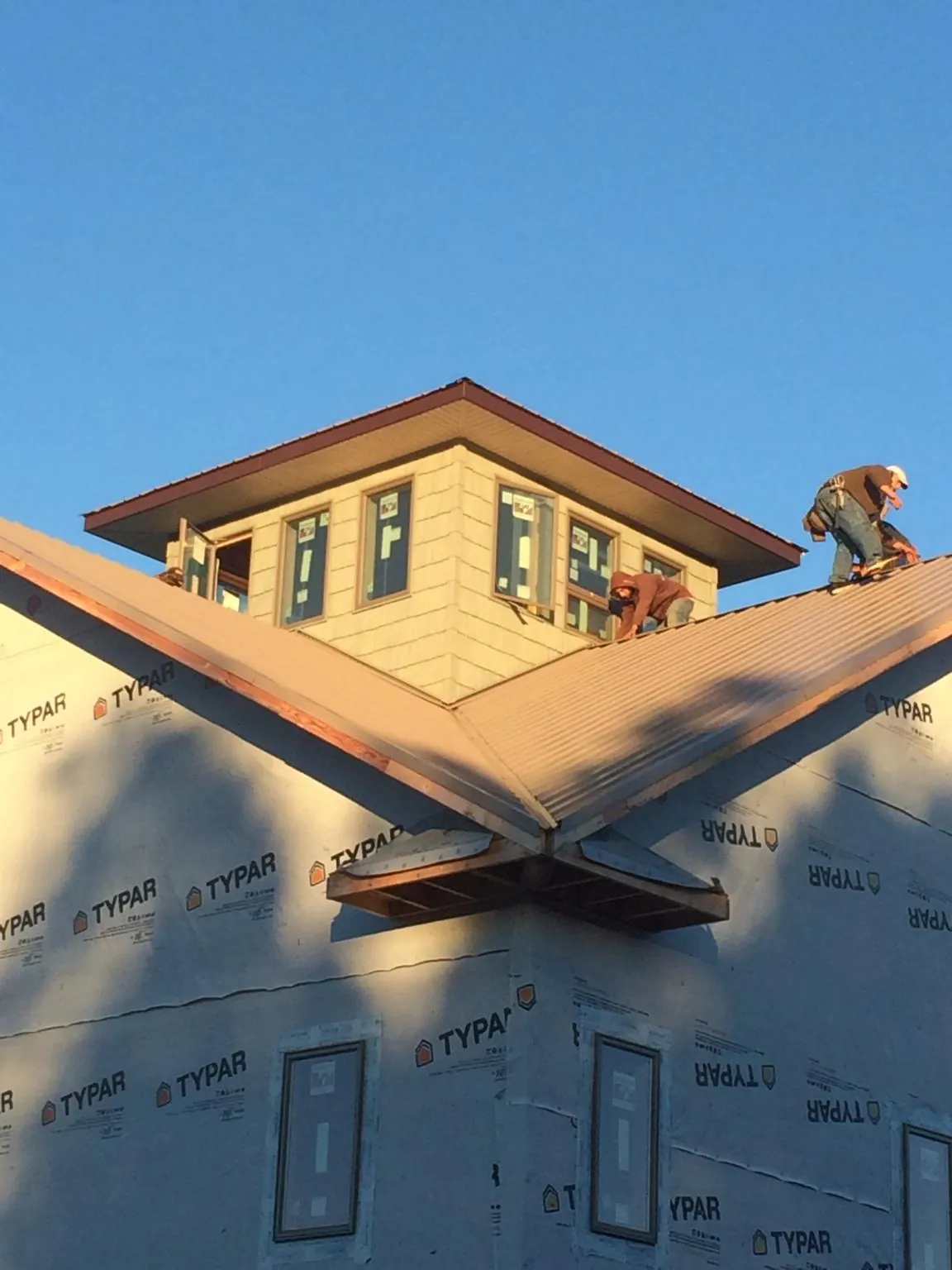 Roofers working around a rooftop cupola on a new metal roof at sunset — Roof Waterproofing in Altaville by Roofing Brothers